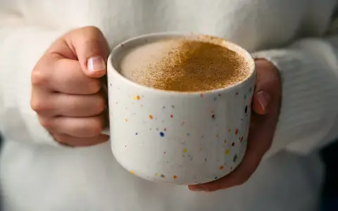 Ciepły napój w kolorowym kubku, posypany cynamonem. Czy to chai latte? Idealny na chłodne dni.