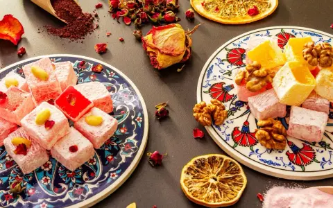 Kolorowe tureckie przysmaki, w tym lokum z pistacjami i orzechami, ozdobione suszonymi różami i plasterkami pomarańczy.