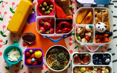 Kolorowy lunchbox z owocami, warzywami, kanapką i słodkościami to idealne szybkie śniadanie dla dzieci.