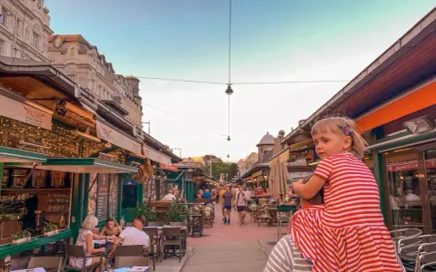 Wiedeń rynek tętni życiem. Dziewczynka na ramionach taty podziwia gwarne uliczki z restauracjami i sklepikami.