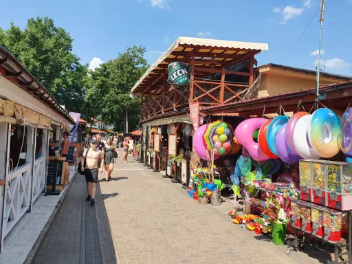 Skorzęcin atrakcje: kolorowe koła do pływania, zabawki plażowe i budki z grami na deptaku.