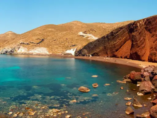 Santorini plaże: Czerwona plaża z turkusową wodą i skalistymi klifami.