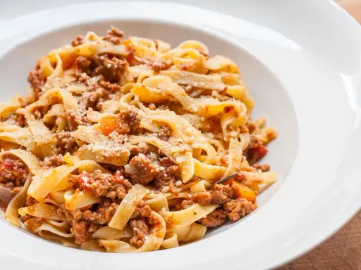 Pyszne tagliatelle z bogatym sosem mięsnym, posypane parmezanem. Idealny spaghetti bolognese przepis oryginalny na obiad.