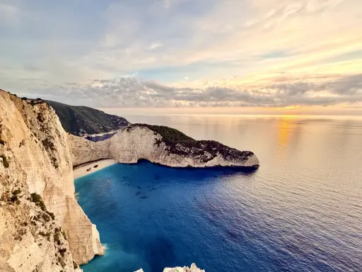 Zachód słońca nad Navagio, słynną zatoką wraku na Zakynthos. Białe klify, turkusowa woda i wrak statku tworzą malowniczy krajobraz.