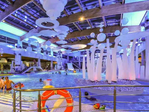 Wesoła zabawa w aquaparku w Sopocie, mnóstwo ludzi cieszy się basenem i atrakcjami. Warto sprawdzić aquapark Sopot opinie przed wizytą.