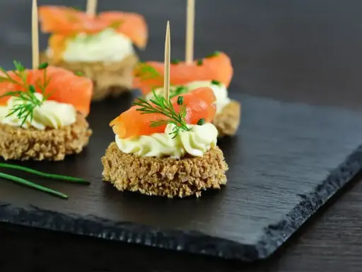 Eleganckie przystawki z łososiem i kremowym serkiem na chrupkim pieczywie, ozdobione koperkiem. Idealne na przyjęcie.
