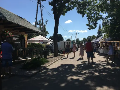 Spacer po targu w upalny dzień. Ludzie oglądają stoiska, szukając lokalnych produktów i pamiątek. Tleń atrakcje oferują wiele możliwości spędzenia wolnego czasu.