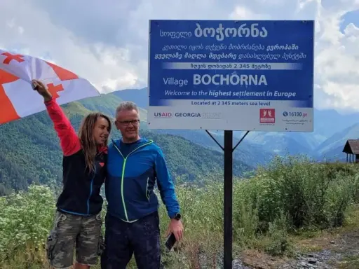 Para podróżników z flagą Gruzji w Bochorna, najwyżej położonej osadzie w Europie. Odpowiedź na pytanie: czy w Gruzji jest bezpiecznie? Tak!