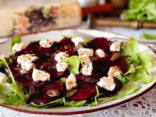 Pyszne carpaccio z buraka z serem feta, rukolą i pestkami dyni na talerzu.