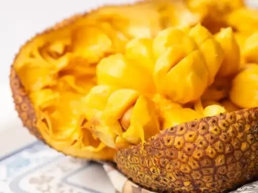Odkryj smak jackfruit po polsku! Soczyste, żółte miąższowe segmenty owocu w skorupie.