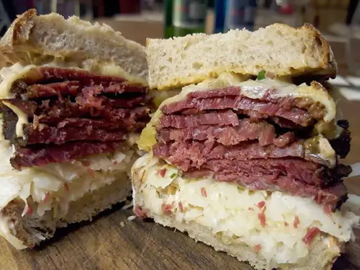 Pyszny reuben sandwich z grubymi plastrami wołowiny, kiszoną kapustą i serem, podany na chlebie żytnim.