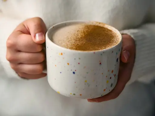 Ciepły napój w kolorowym kubku, posypany cynamonem. Czy to chai latte? Idealny na chłodne dni.
