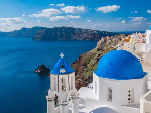 Santorini, Grecja. Białe domy z niebieskimi kopułami na tle morza. Ciekawe miejsca i widoki.
