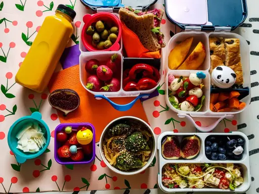 Kolorowy lunchbox z owocami, warzywami, kanapką i słodkościami to idealne szybkie śniadanie dla dzieci.