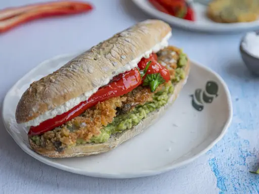 Pyszna kanapka ze śledziem, awokado i pieczoną papryką na chrupiącej bułce. Idealna na szybki lunch.