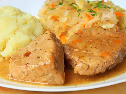 Soczysta pieczeń z szynki wieprzowej w sosie, podana z ziemniakami i kapustą. Pyszny obiad!