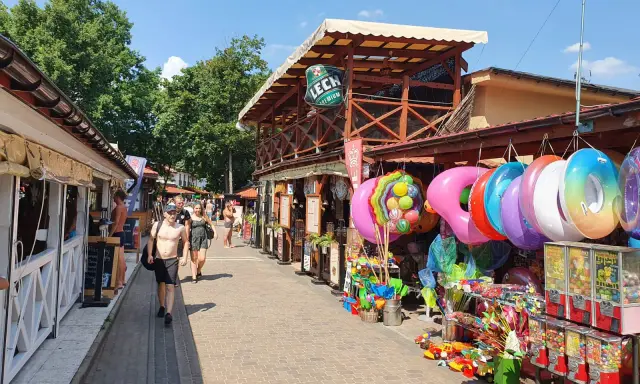 Skorzęcin atrakcje: kolorowe koła do pływania, zabawki plażowe i budki z grami na deptaku.