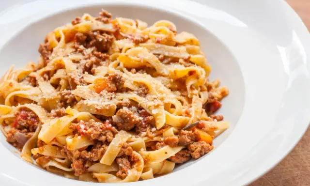 Pyszne tagliatelle z bogatym sosem mięsnym, posypane parmezanem. Idealny spaghetti bolognese przepis oryginalny na obiad.