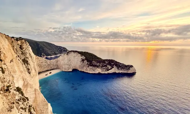 Zachód słońca nad Navagio, słynną zatoką wraku na Zakynthos. Białe klify, turkusowa woda i wrak statku tworzą malowniczy krajobraz.