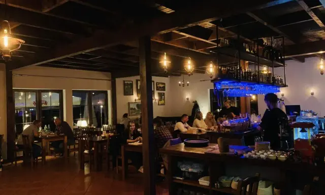 Wnętrze restauracji z ludźmi przy stołach i barem.