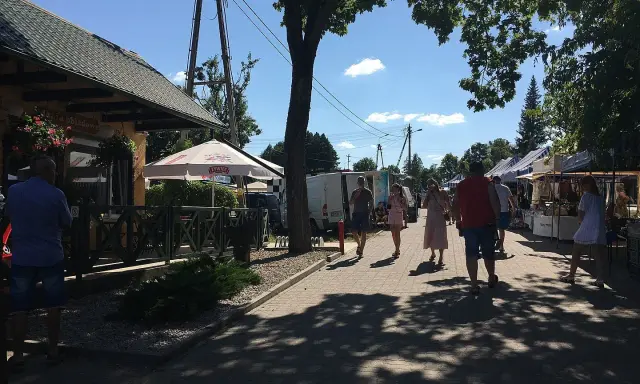 Spacer po targu w upalny dzień. Ludzie oglądają stoiska, szukając lokalnych produktów i pamiątek. Tleń atrakcje oferują wiele możliwości spędzenia wolnego czasu.