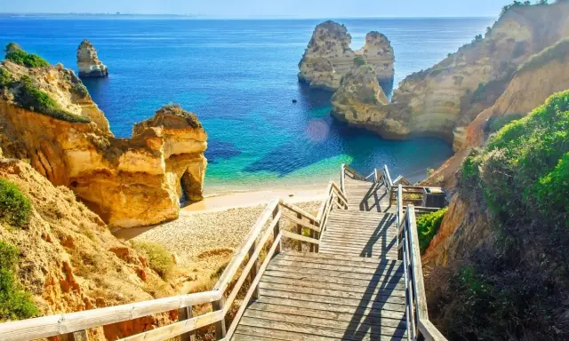 Malownicze klify i turkusowe morze w Portugalii. Schody prowadzą na ukrytą plażę. Ciekawe miejsca czekają!