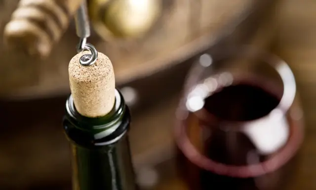 Korek wyjmowany z butelki, kieliszek wina i beczka. Czy wino ma datę ważności? To pytanie zadaje sobie wielu miłośników tego trunku.
