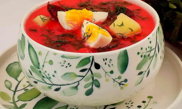 Aksamitna zupa z botwiny z ziemniakami, ozdobiona jajkiem i koperkiem, podana w miseczce z motywem roślinnym.
