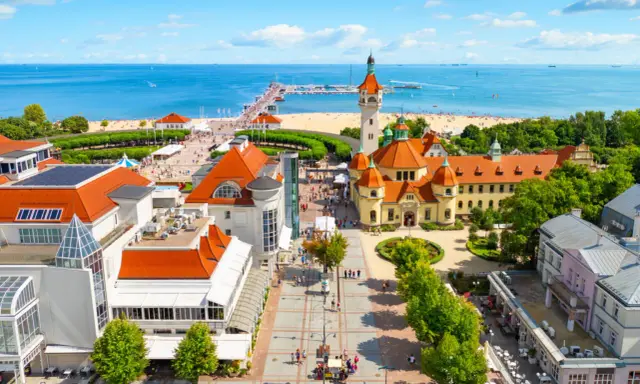 Malownicze miejscowosci nad morzem z molo, plażą i zabytkową architekturą.