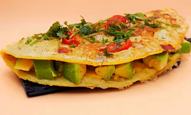 Omlet z awokado, pomidorkami i ziołami, pyszne i zdrowe śniadanie.