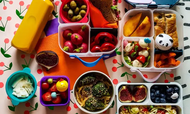 Kolorowy lunchbox z owocami, warzywami, kanapką i słodkościami to idealne szybkie śniadanie dla dzieci.