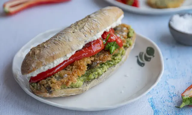 Pyszna kanapka ze śledziem, awokado i pieczoną papryką na chrupiącej bułce. Idealna na szybki lunch.