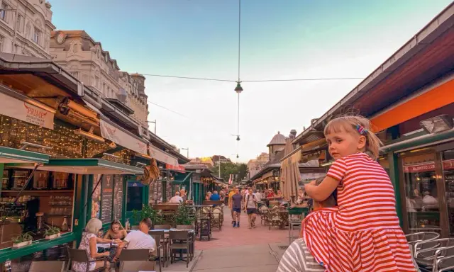 Wiedeń rynek tętni życiem. Dziewczynka na ramionach taty podziwia gwarne uliczki z restauracjami i sklepikami.