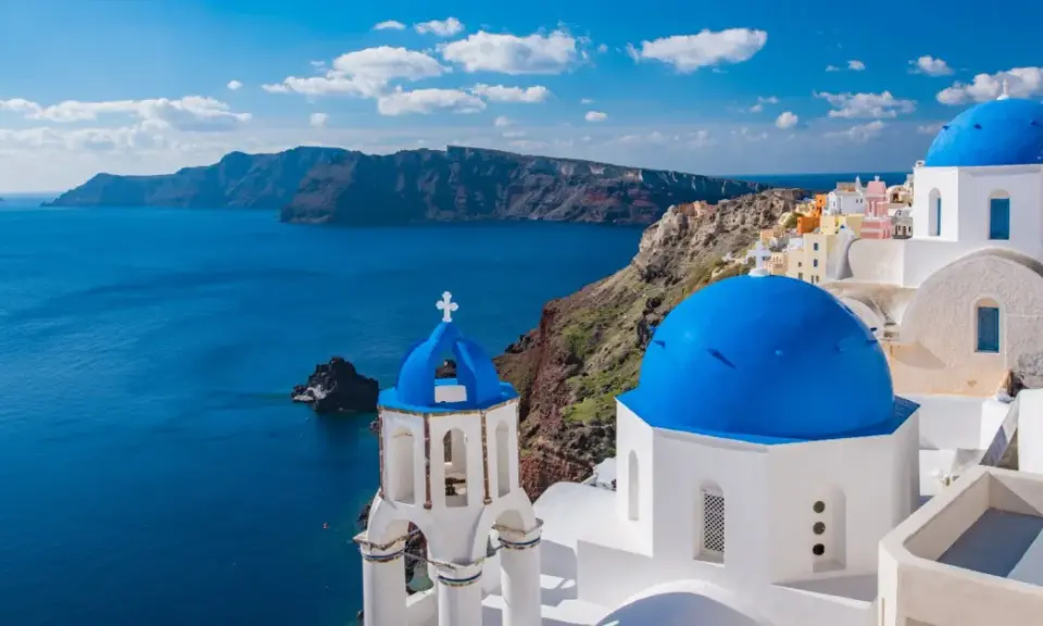 Santorini, Grecja. Białe domy z niebieskimi kopułami na tle morza. Ciekawe miejsca i widoki.