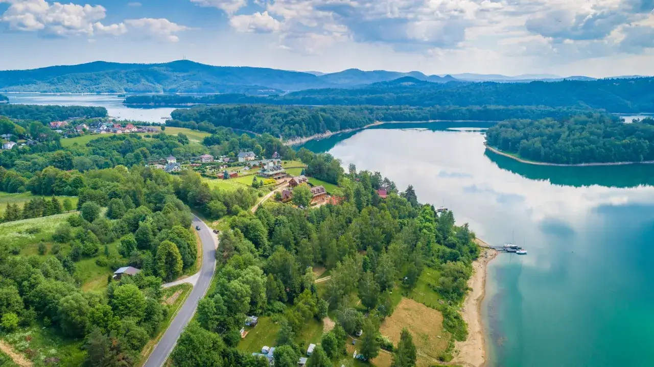 Bieszczady: malownicza zatoka Jeziora Solińskiego z zabudowaniami i lasami. Warto zobaczyć to miejsce!
