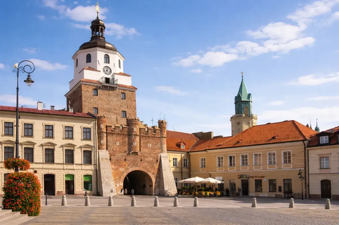 Lublin nietypowe atrakcje: Brama Krakowska i Rynek z kawiarnianymi ogródkami. Wieże i kamienice tworzą malowniczy krajobraz.