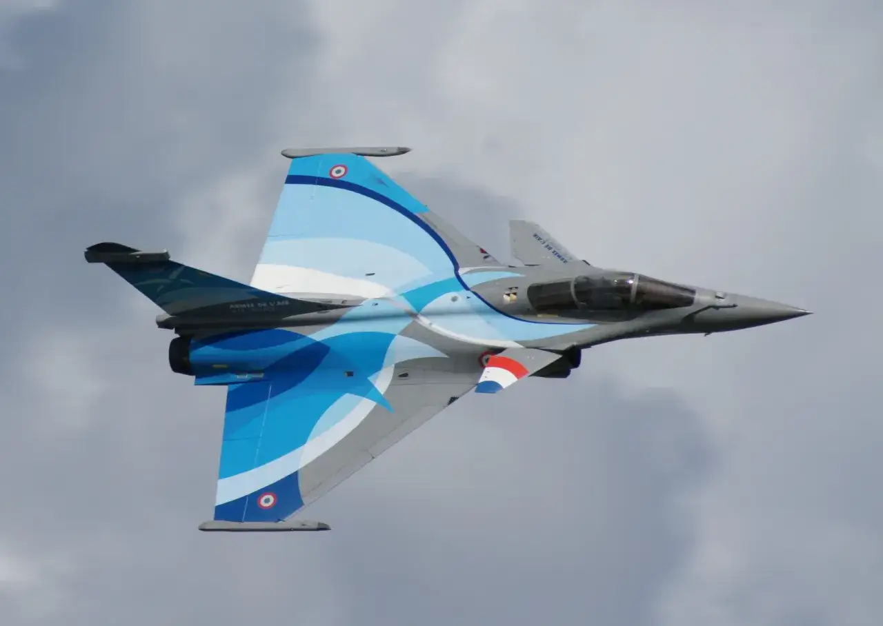 Francuski myśliwiec z malowaniem fal w odcieniach niebieskiego i szarości podczas air show w Radomiu.