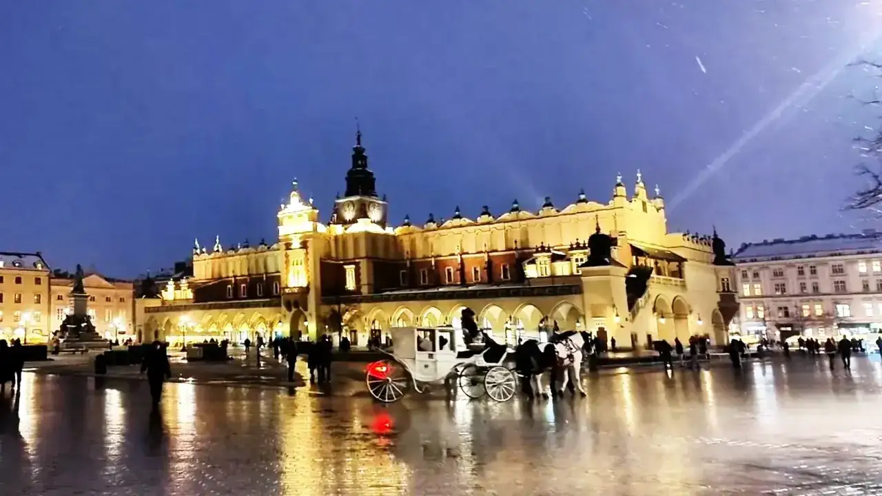 Wieczorny Rynek w Krakowie, Sukiennice oświetlone, dorożka na mokrym bruku. Ciekawe ciekawostki o Krakowie czekają!