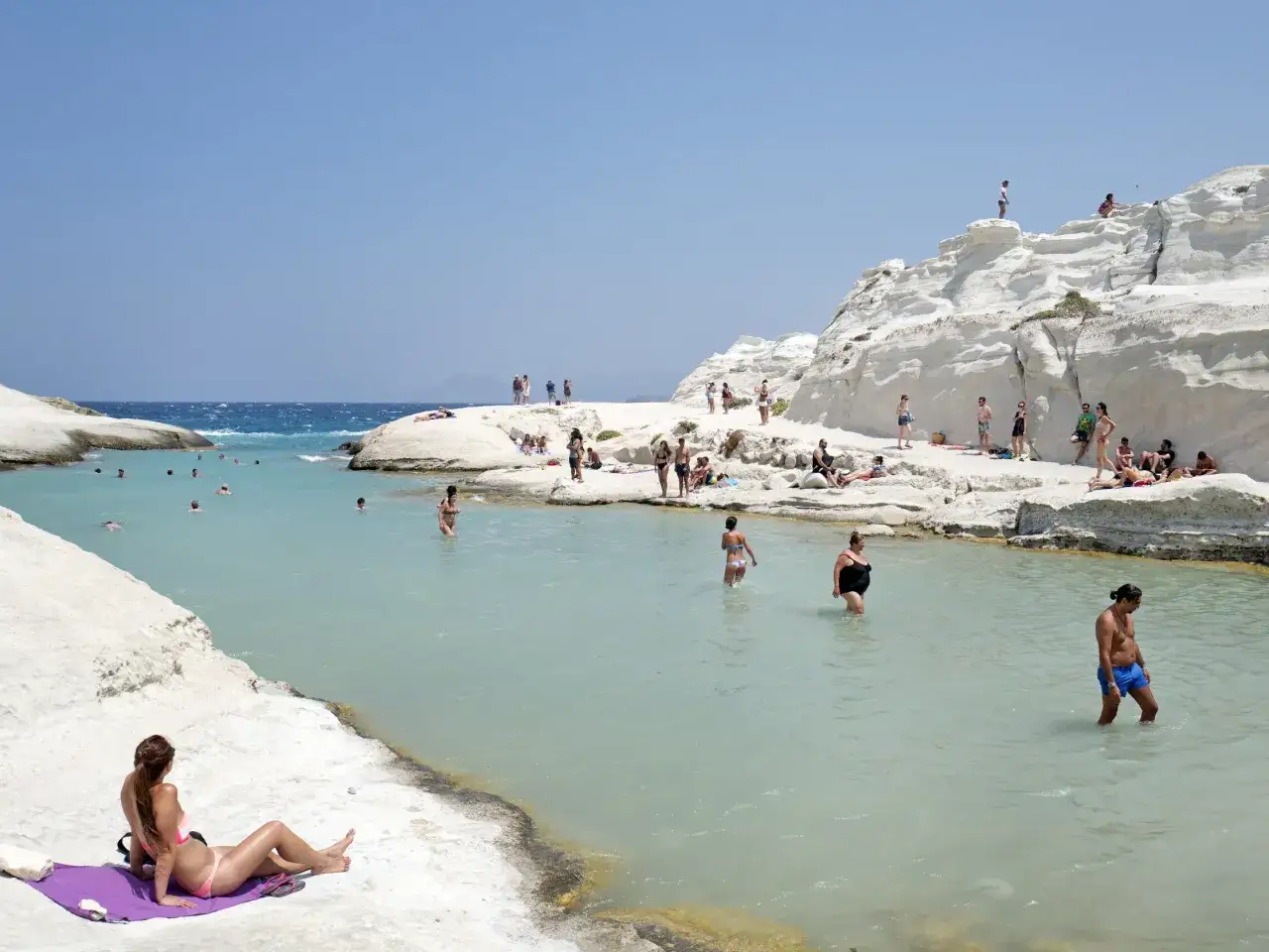 Piękna plaża w Grecji z turkusową wodą i białymi skałami. Ludzie kąpią się i opalają. Ciekawe ciekawostki o grecji czekają na odkrycie!