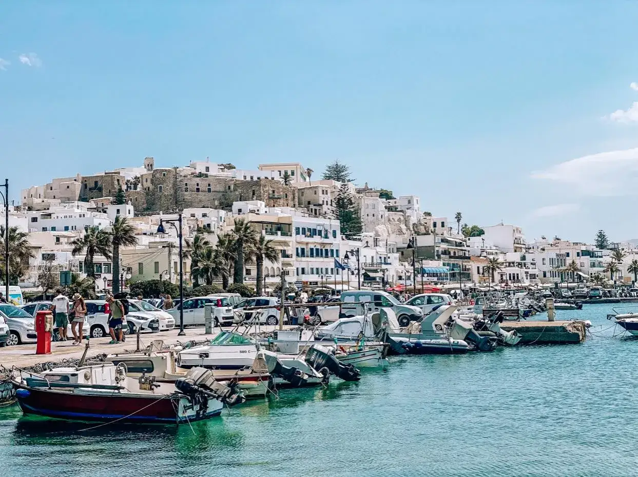 Port na Naxos, z białymi budynkami wznoszącymi się na wzgórzu i łodziami kołyszącymi się na turkusowej wodzie.