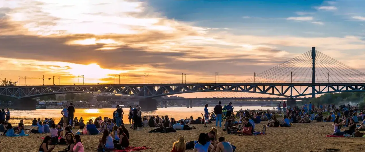 Zachód słońca nad Wisłą, tłumy ludzi na plaży i mosty – idealne miejsce, gdzie na spacer w Warszawie.